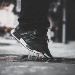 Jemand springt hoch aus Pfütze, mit Adidas Campus 00 Schuhen, Schwarz-weiß Foto