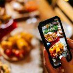 Nahaufnahme einer nicht wiederzuerkennenden jungen Frau, die mit ihrem Mobiltelefon ein Foto oder Video von einem schönen Weihnachtstisch macht. Bloggerin fotografiert Essen beim Weihnachtsessen.