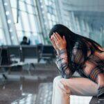 Eine Frau sitzt verzweifelt in einem Flughafen und hält sich den Kopf. Kanzlei Ra-Hartung bietet Unterstützung bei Flugausfällen und Reisemängeln.