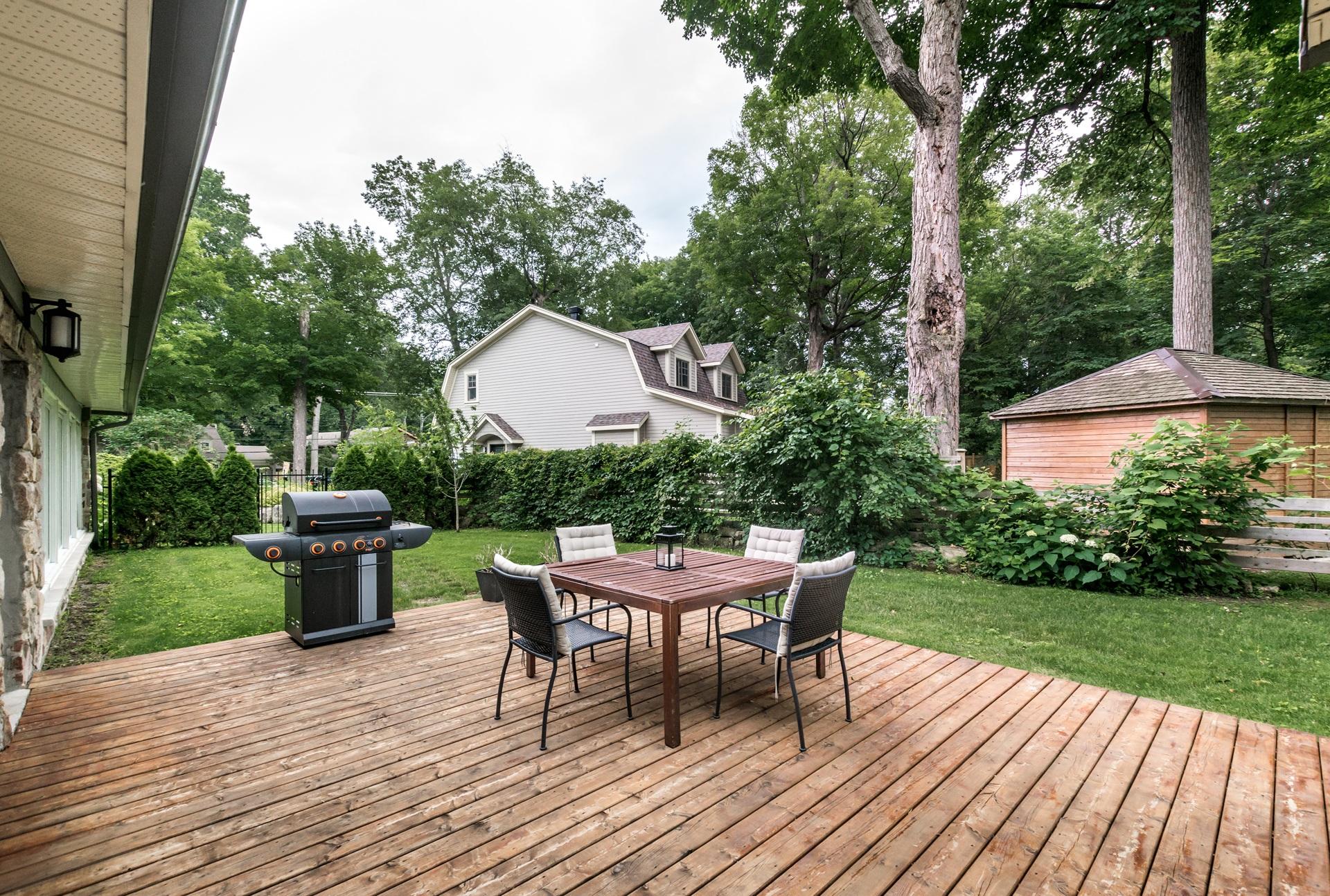 Holzterrasse im Garten mit Sitzmöbeln und Grill | Terrassenüberdachung